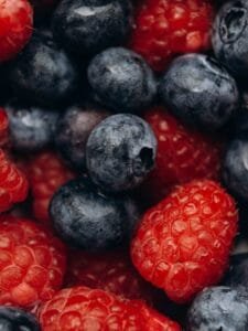 A vibrant and detailed close-up of fresh, colorful blueberries and raspberries.